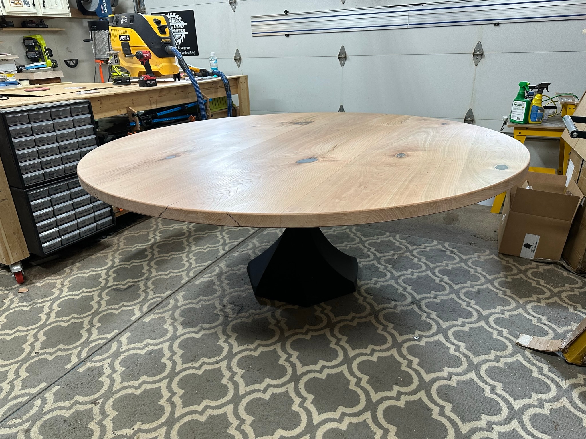 Round white oak dining table with geometric pedestal base